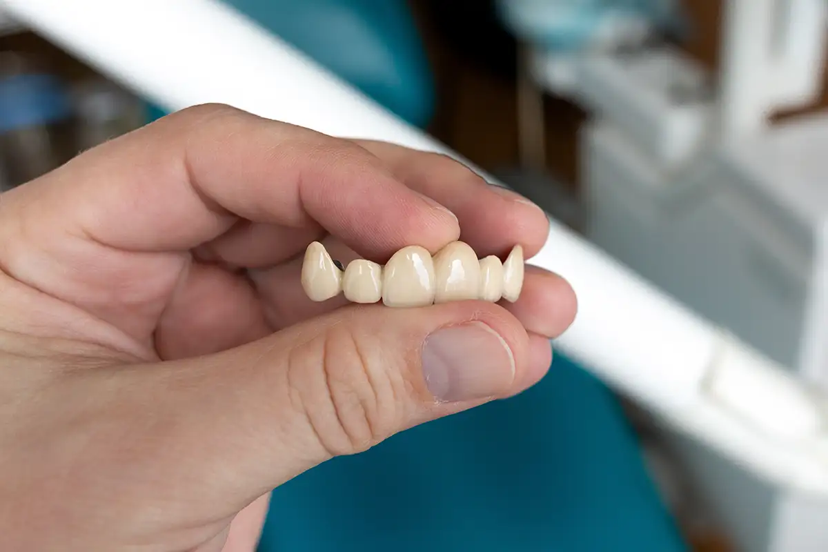 A hand holding a ceramic bridge